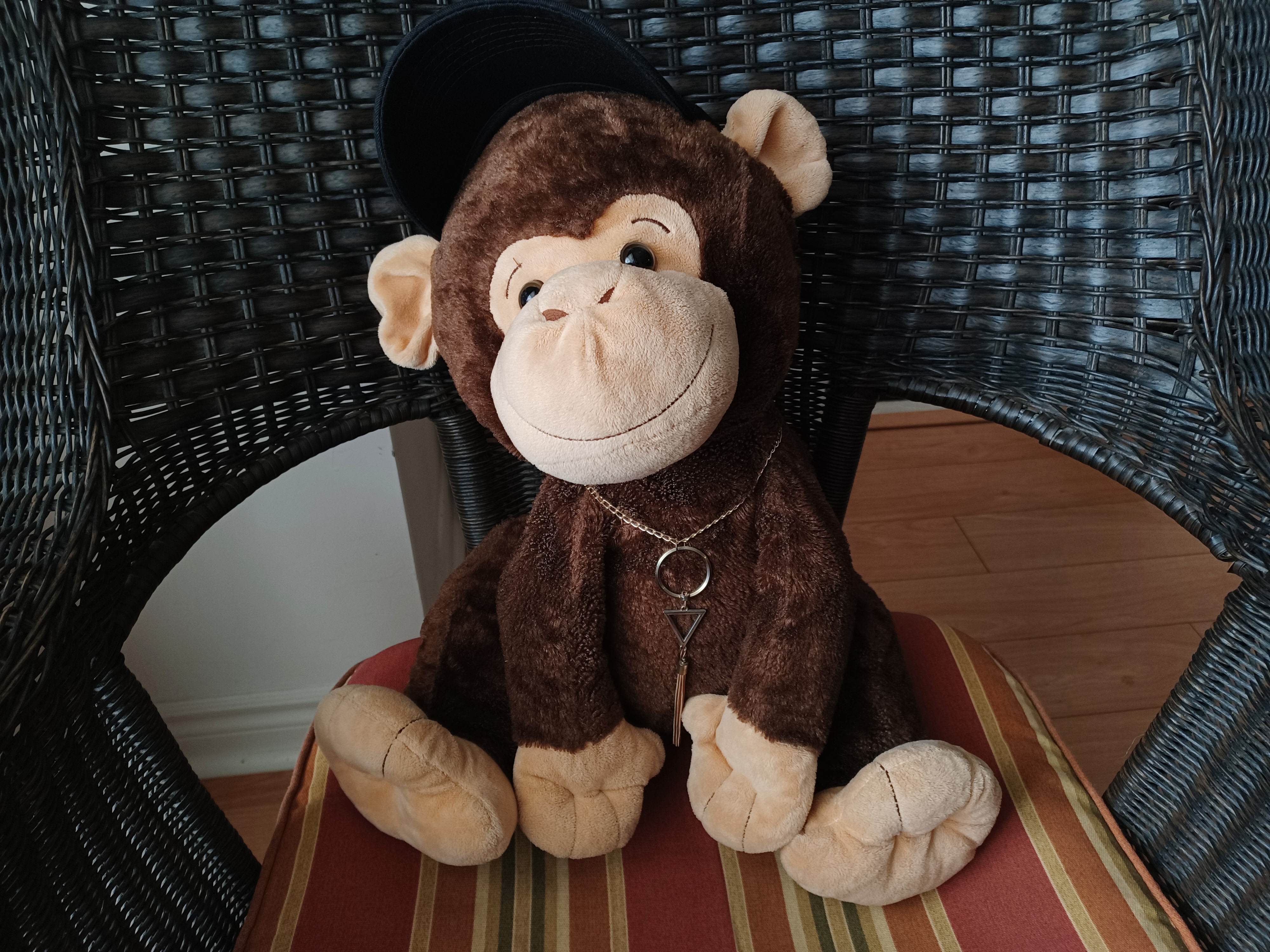 stuffed monkey on wearing black cap and chain sitting on chair